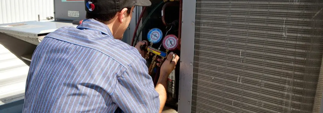HVAC technician servicing a condenser unit in Shively
